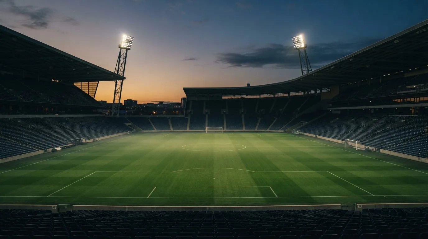 Een leeg voetbalstadion met lichtmasten bij schemering