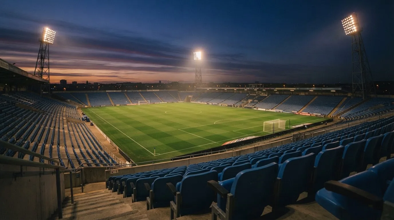 Een leeg voetbalstadion met lichtmasten bij schemering