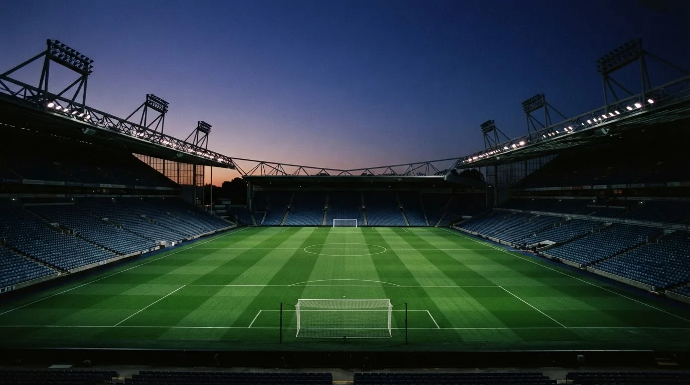 Een leeg voetbalstadion met lichtmasten bij schemering