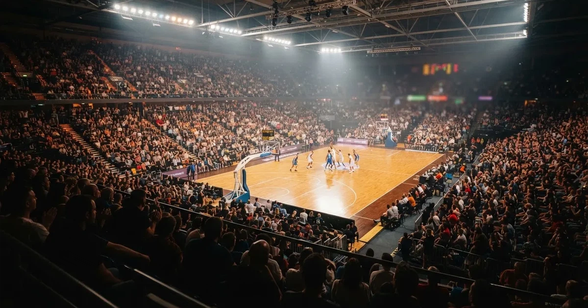 Een volle sporthal onder schijnwerpers, van grote afstand gefotografeerd