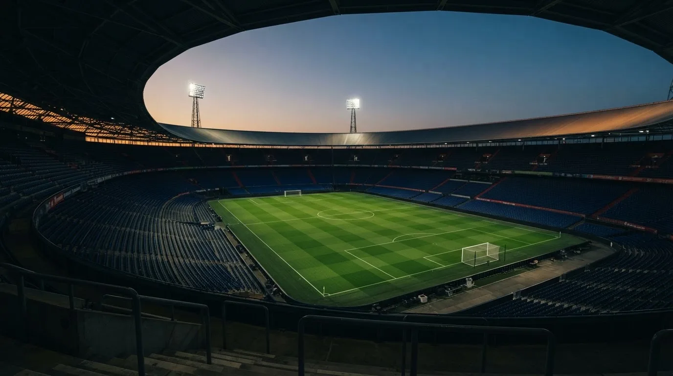 Een leeg voetbalstadion met lichtmasten bij schemering