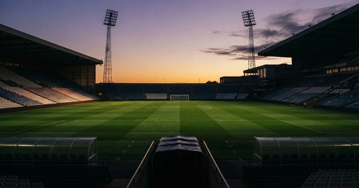 Een leeg voetbalstadion met lichtmasten bij schemering