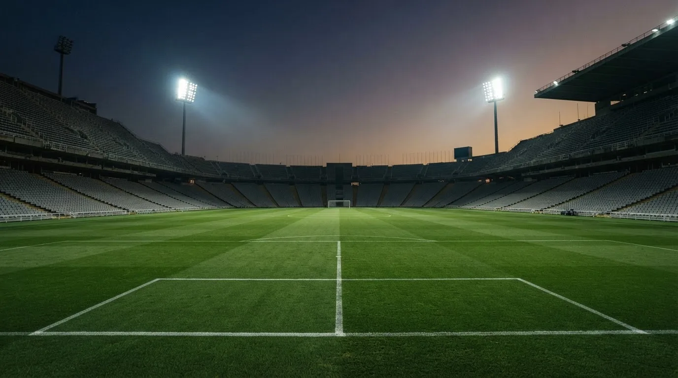 Een leeg voetbalstadion met lichtmasten bij schemering