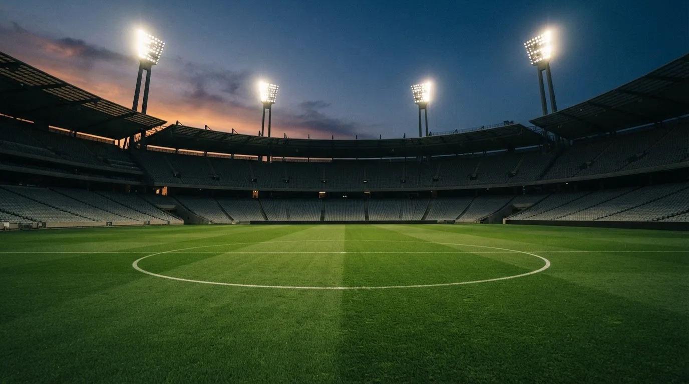 Een leeg voetbalstadion met lichtmasten bij schemering