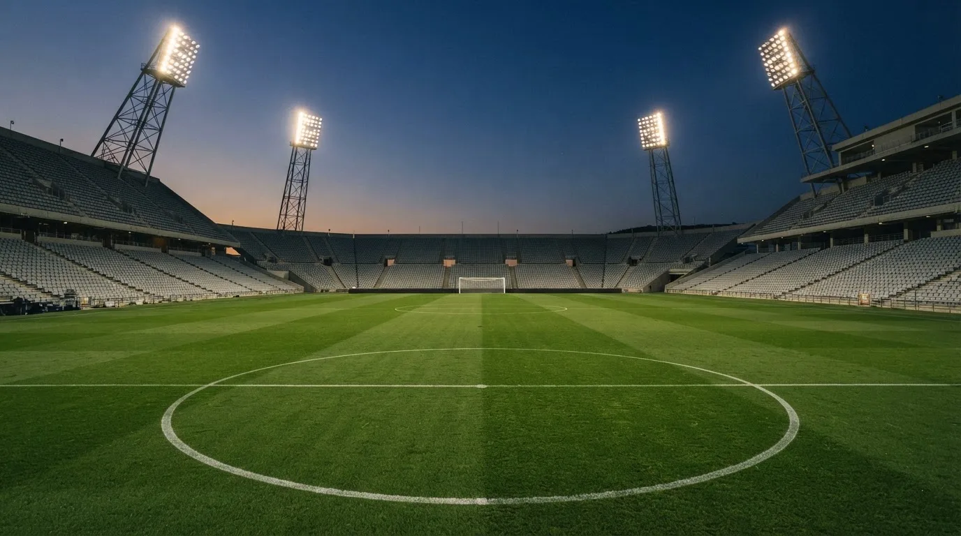 Een leeg voetbalstadion met lichtmasten bij schemering