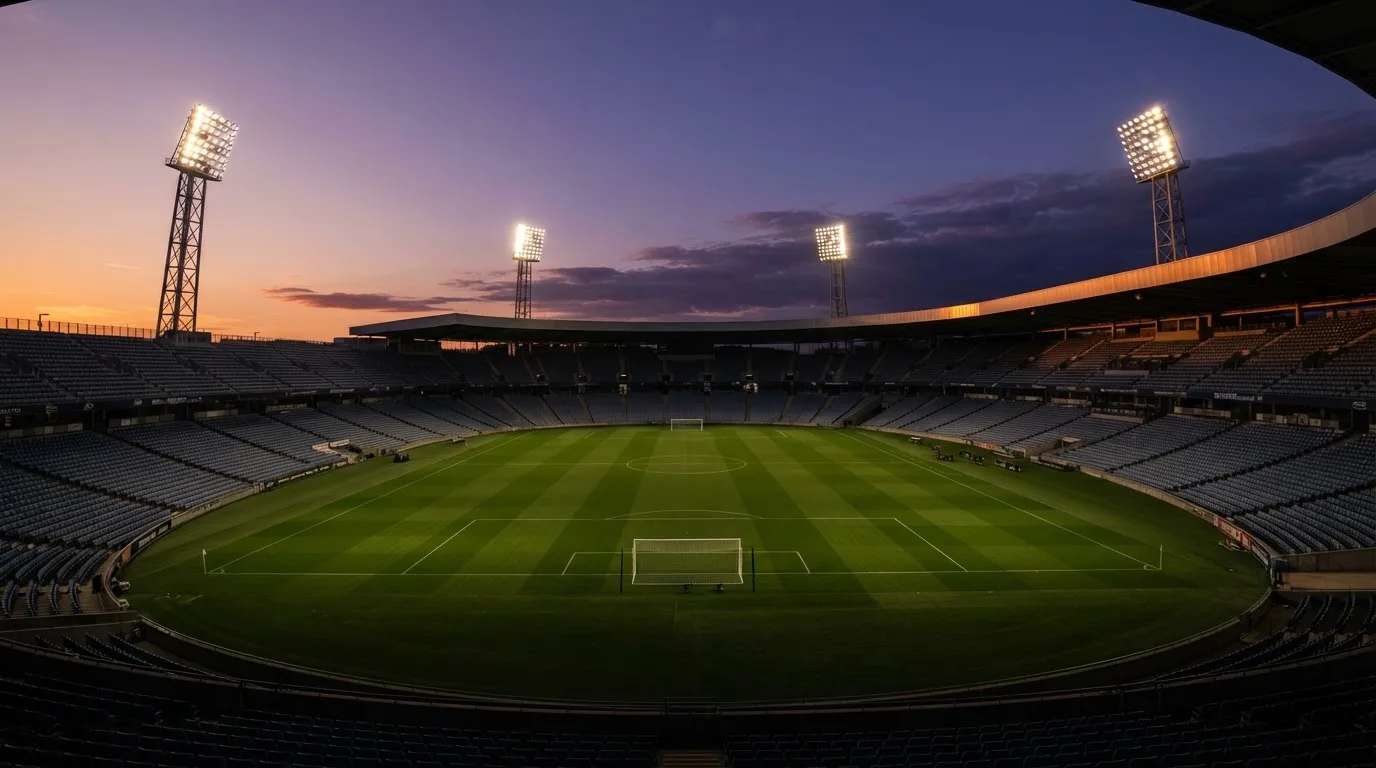 Een leeg voetbalstadion met lichtmasten bij schemering