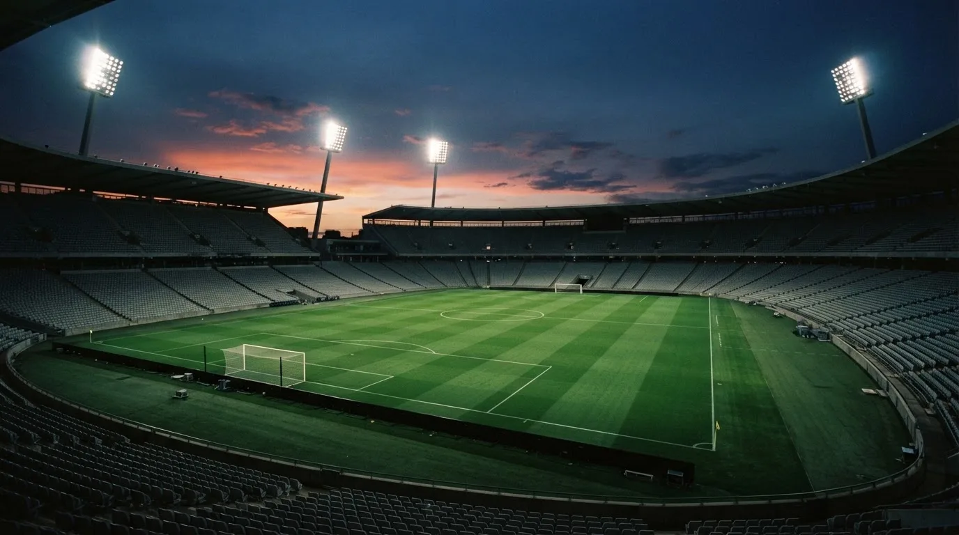 Een leeg voetbalstadion met lichtmasten bij schemering