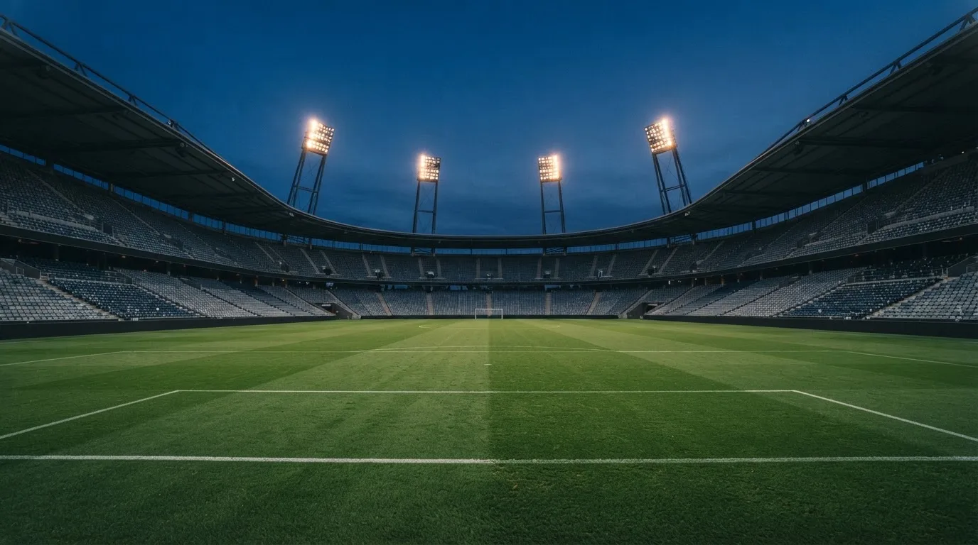 Een leeg voetbalstadion met lichtmasten bij schemering