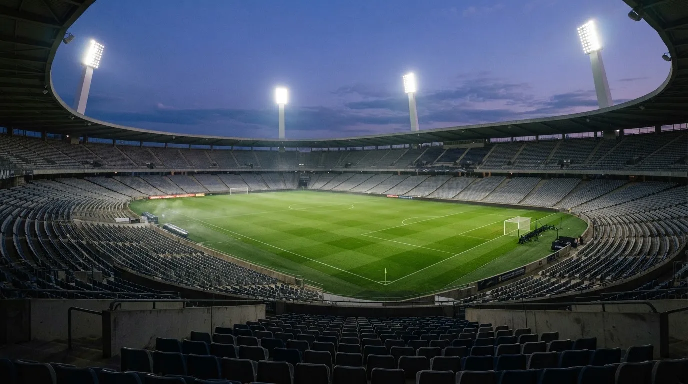 Een leeg voetbalstadion met lichtmasten bij schemering