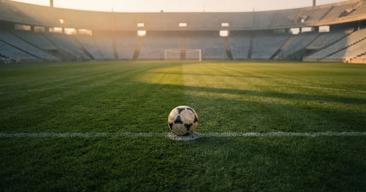 Een voetbal op de middenstip van een grasveld in het ochtendlicht