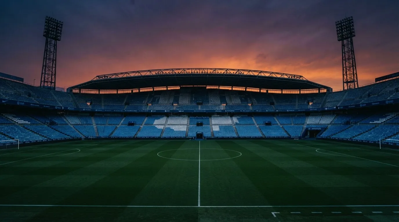 Een leeg voetbalstadion met lichtmasten bij schemering