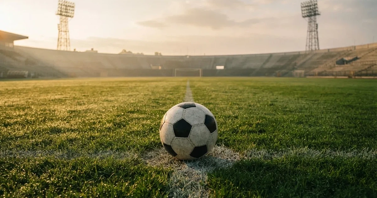 Een voetbal op de middenstip van een grasveld in het ochtendlicht